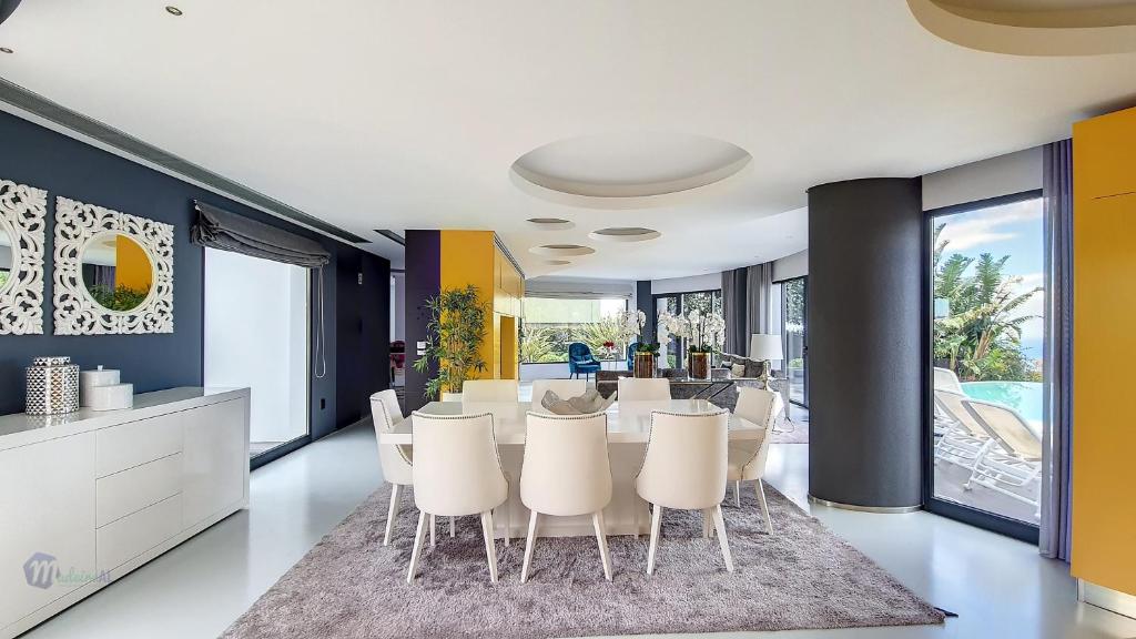 Un comedor con una mesa y sillas blancas. en Villa Bonsai, en Arco da Calheta
