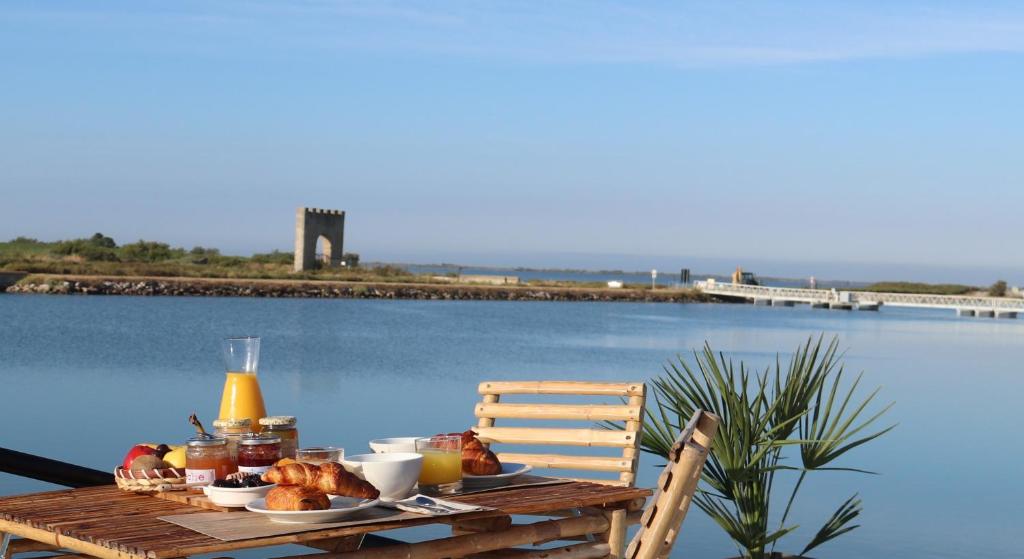 a table with food on it next to a body of water at Peniche Alphonsia Maria in Villeneuve-lès-Maguelonne