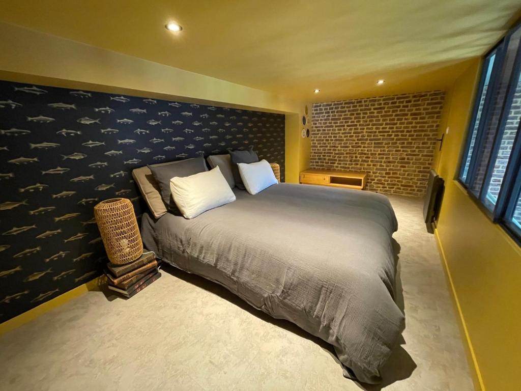 een slaapkamer met een groot bed en een bakstenen muur bij "Curiosités", place de parking privative, centre ville in Dieppe