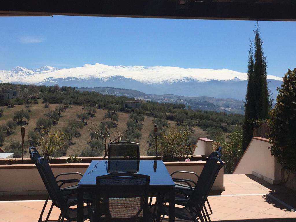 una mesa y sillas en un balcón con montañas cubiertas de nieve en Villa Alfaguara, en Granada
