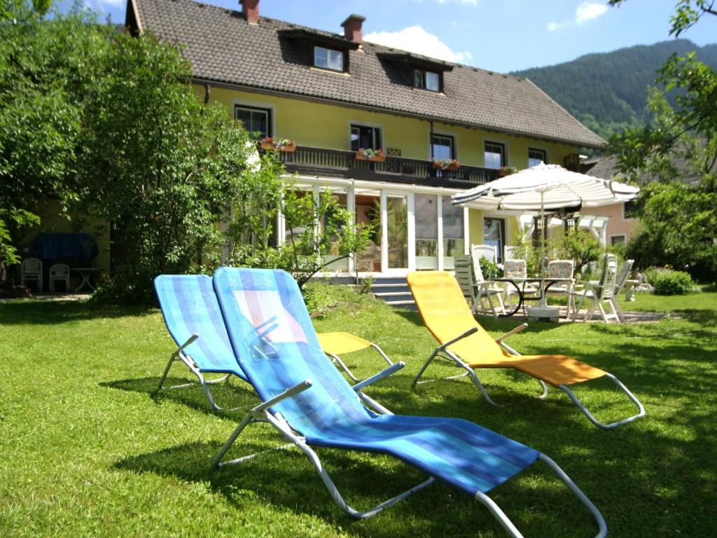 three chairs sitting in the grass in front of a house at Charming Apartment in Feld am See 100 m from Lake in Feld am See