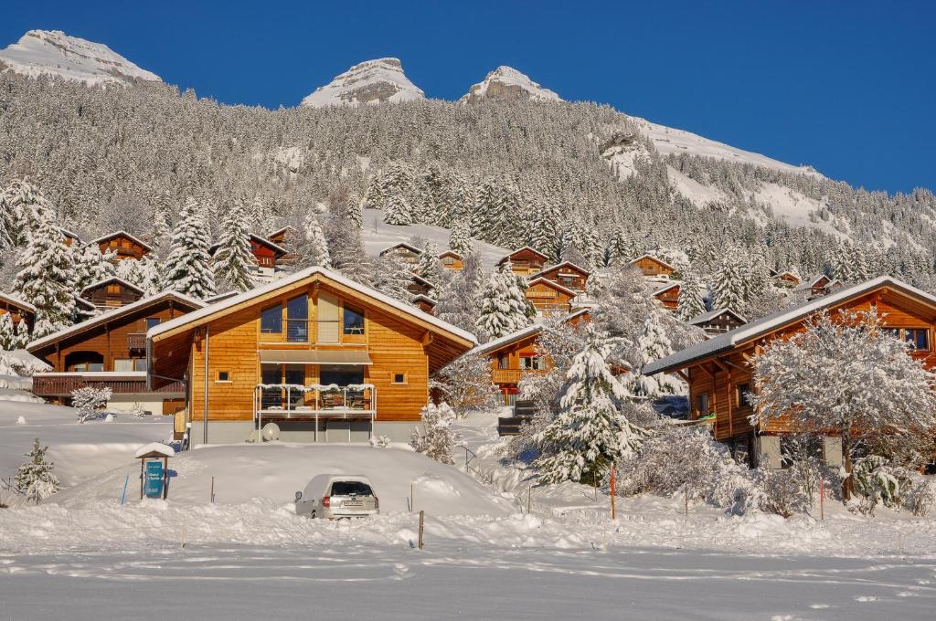 ein Blockhaus im Schnee mit Bergen im Hintergrund in der Unterkunft Bed & Breakfast l'Epicéa in Leysin