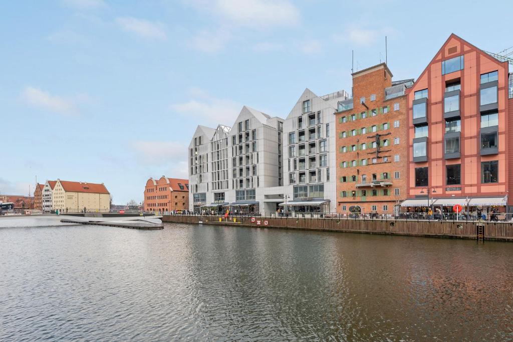 a group of buildings next to a river with buildings at Downtown Apartments Riverside Granaria in Gdańsk