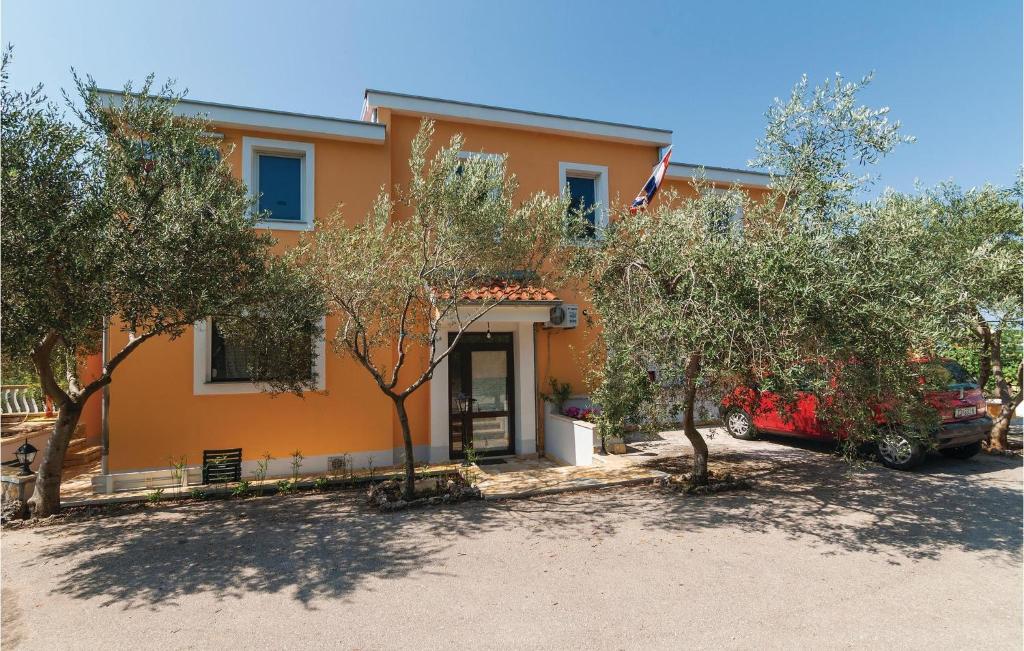 pomarańczowy dom z czerwoną ciężarówką zaparkowaną przed nim w obiekcie One-Bedroom Apartment In Posedarje w mieście Posedarje