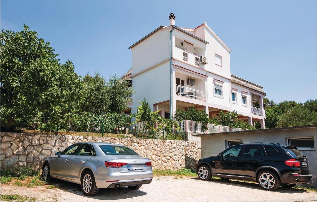 dwa samochody zaparkowane przed domem w obiekcie One-Bedroom Apartment In Posedarje w mieście Posedarje