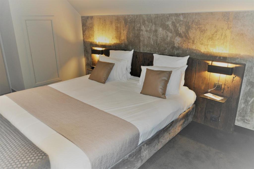 - une chambre dotée d'un grand lit avec des draps et des oreillers blancs dans l'établissement Hotel Saint Daniel, à Péruwelz