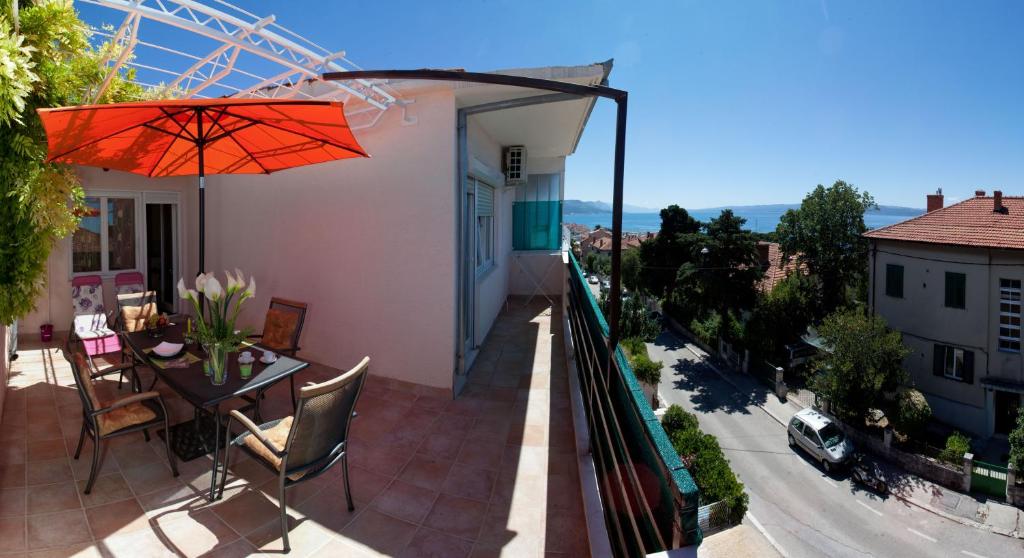 a balcony with a table and an umbrella at Apartments Beautiful Sandy Beach in Split
