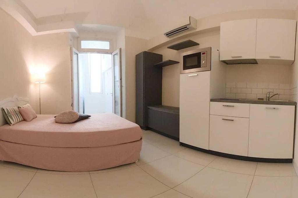 une petite chambre avec un lit et une cuisine dans l'établissement Studio rénové Hyper Centre- Ajaccio, à Ajaccio