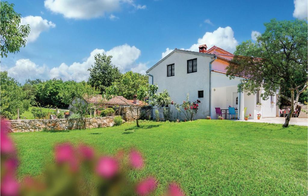 een wit huis met een tuin met roze bloemen bij Awesome Apartment In Sv,petar U Sumi With Wifi in Pamići