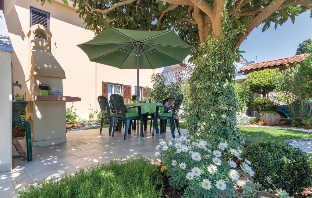 een patio met een tafel en stoelen en een parasol bij 2 Bedroom Amazing Apartment In Valbandon in Fažana