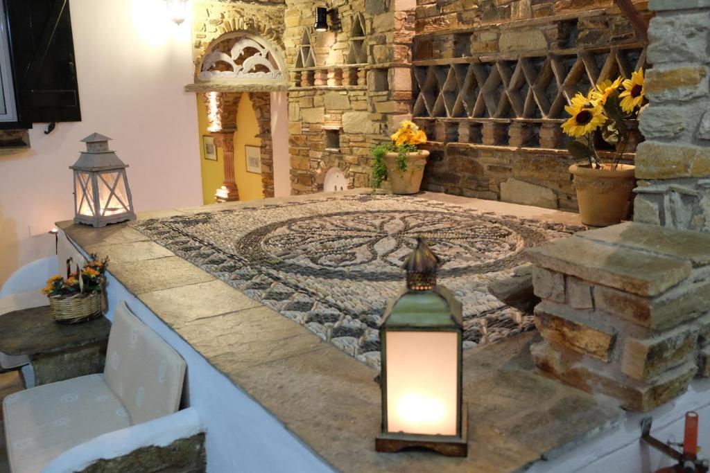 a room with a stone wall and a table with a light at Voreades in Tinos