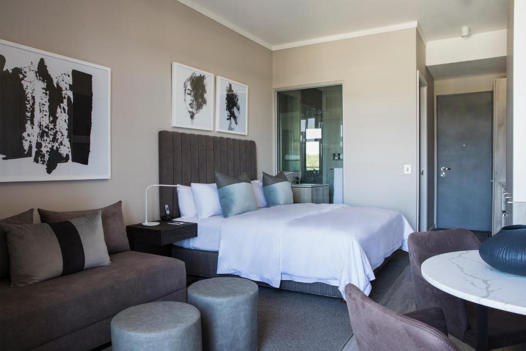 a bedroom with a bed and a living room with a couch at The Capital Menlyn Maine Trilogy in Pretoria