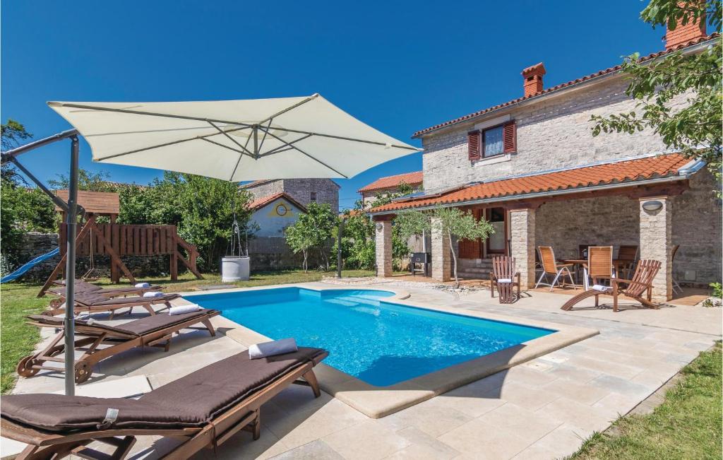 a swimming pool with two chairs and an umbrella at Gorgeous Home In Cabrunici With Wifi in Čabrunići