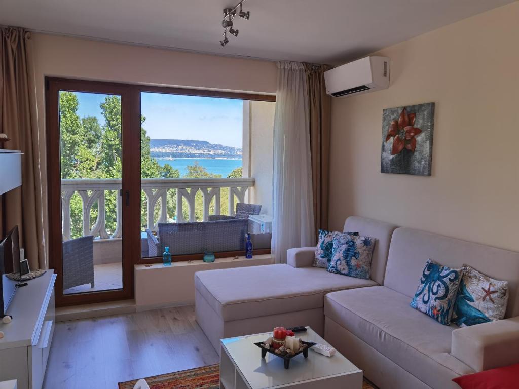 a living room with a couch and a balcony at By the Waves luxury beach apartment in Varna City