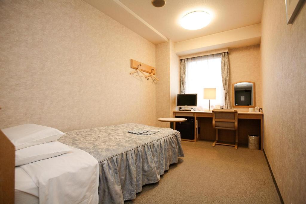 a room with a bed and a desk with a computer at Narita U-City Hotel in Narita