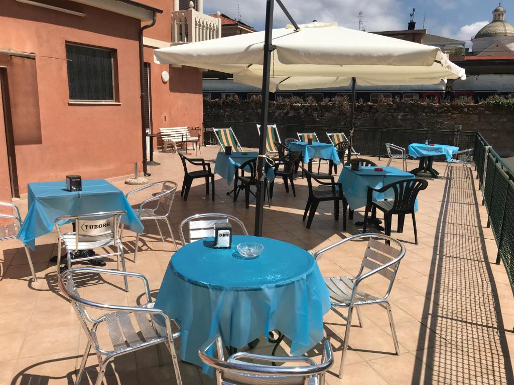 eine Terrasse mit blauen Tischen, Stühlen und einem Sonnenschirm in der Unterkunft Hotel Doria in Chiavari