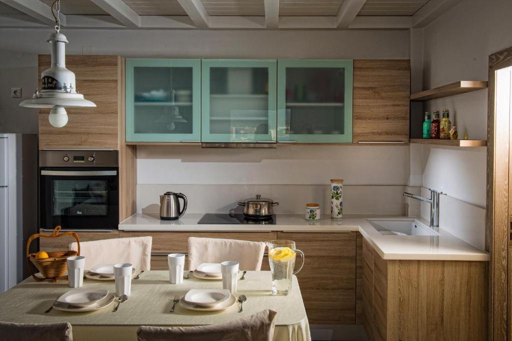 una cocina con mesa y una cocina con armarios verdes en Villa Asterias, en Stalida
