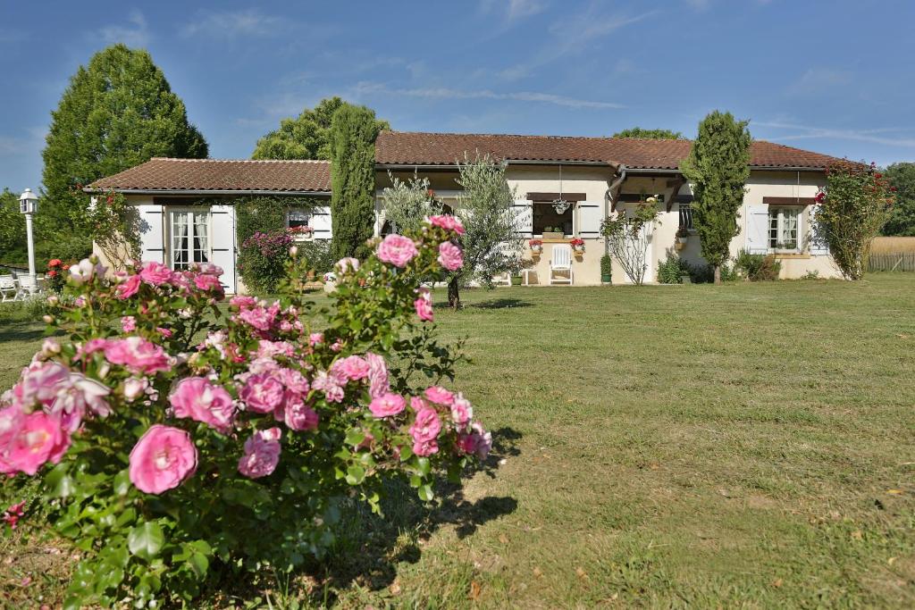 dom z różowymi różami na podwórku w obiekcie L'Ariade w mieście Monpazier