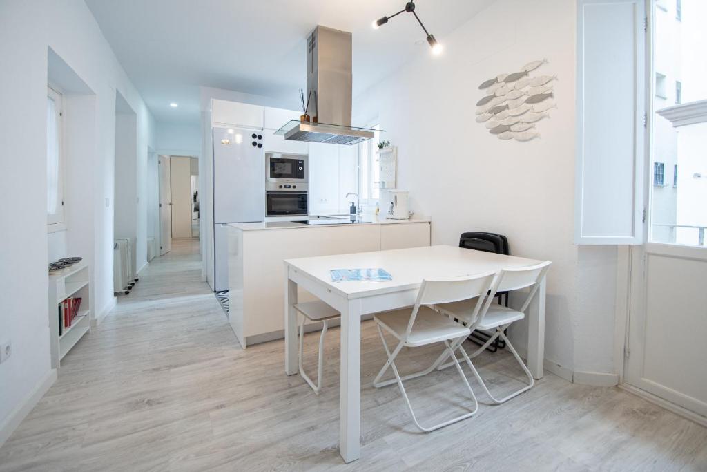 eine weiße Küche mit einem weißen Tisch und Stühlen in der Unterkunft Apartamento Las Lectoras de Cadiz in Cádiz