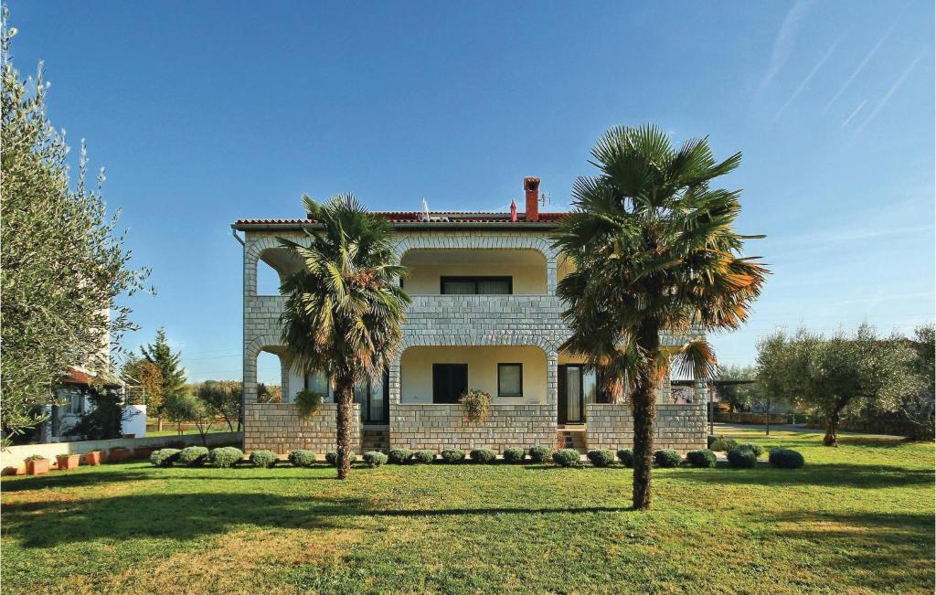 a house with two palm trees in front of it at 3 Bedroom Gorgeous Apartment In Porec in Poreč