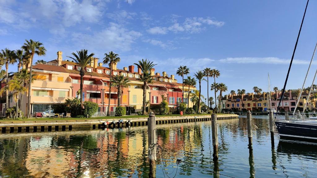 a boat in a body of water with buildings and palm trees at Luxury Penhouse, Sotogrande Marina - Located in an exclusive island of the Marina in Sotogrande