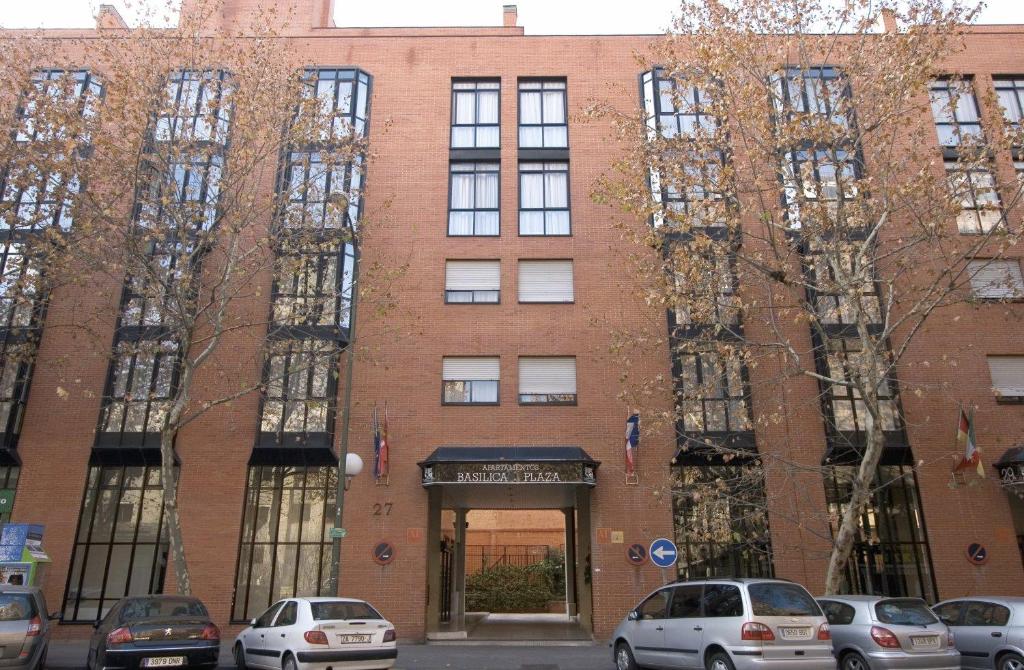 a large brick building with cars parked in front of it at Espahotel Plaza Basílica in Madrid