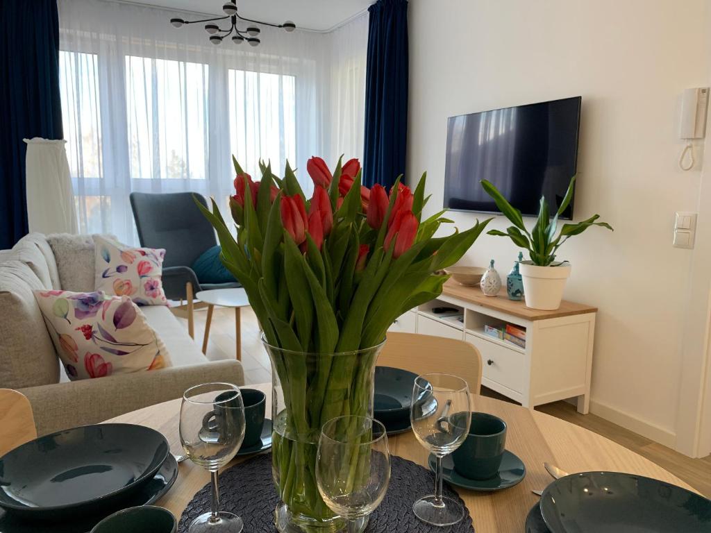 una sala de estar con un jarrón de flores rojas sobre una mesa en Apartamenty Bliska 33 en Bielsko-Biala
