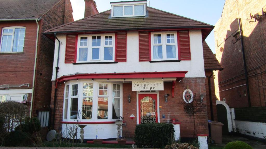 una casa roja y blanca con un cartel. en Longcroft Lodge, en Bridlington