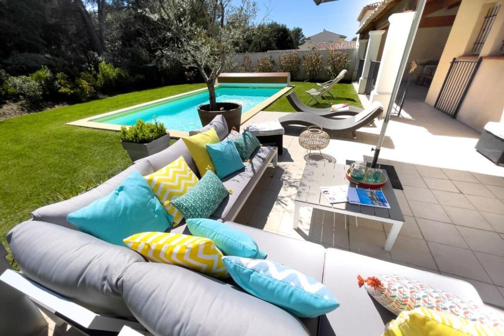 Sofá blanco con almohadas coloridas junto a la piscina en Ma villa en Provence villa de standing et piscine Domaine de Pont-Royal, en Mallemort