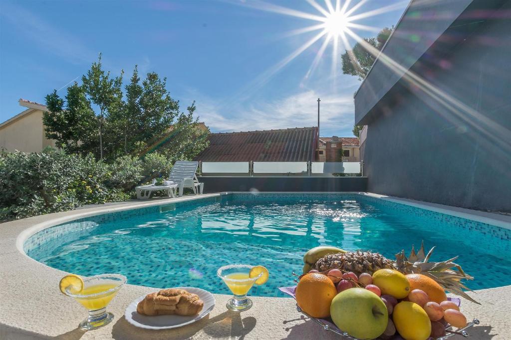 a tray of fruit on a table next to a swimming pool at Apartments Lorenzo in Lokva Rogoznica