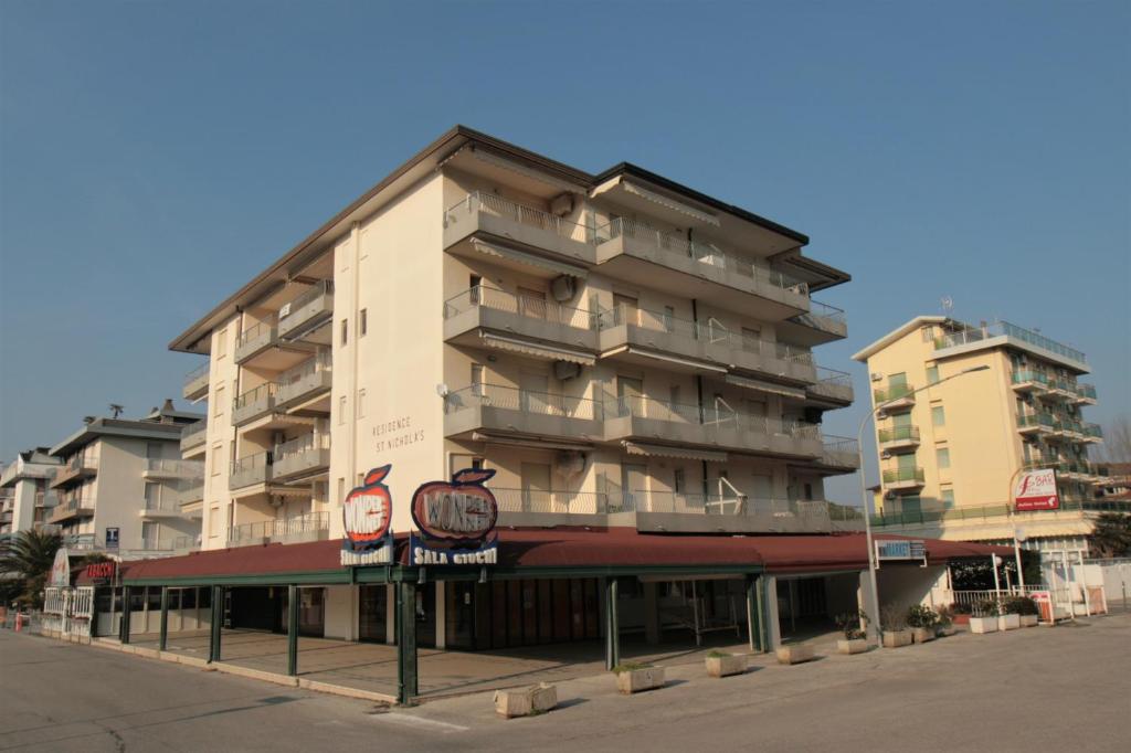 un edificio de apartamentos alto con un cartel delante en San Nichola's en Lido di Jesolo