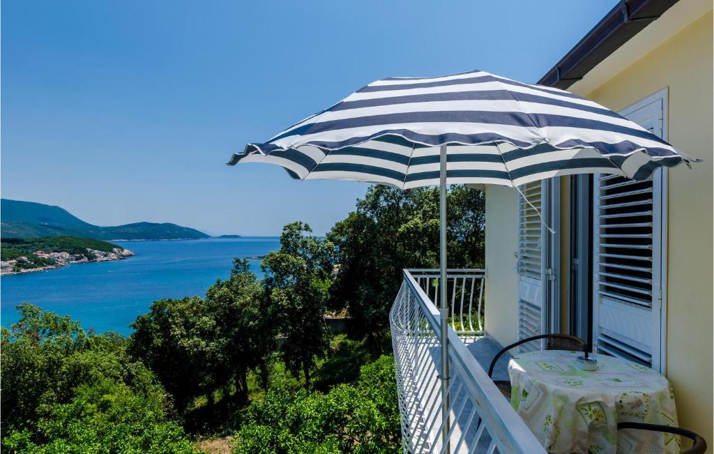 stół z parasolem na balkonie z widokiem na ocean w obiekcie Beautiful Apartment In Gruda With Kitchen w mieście Molunat