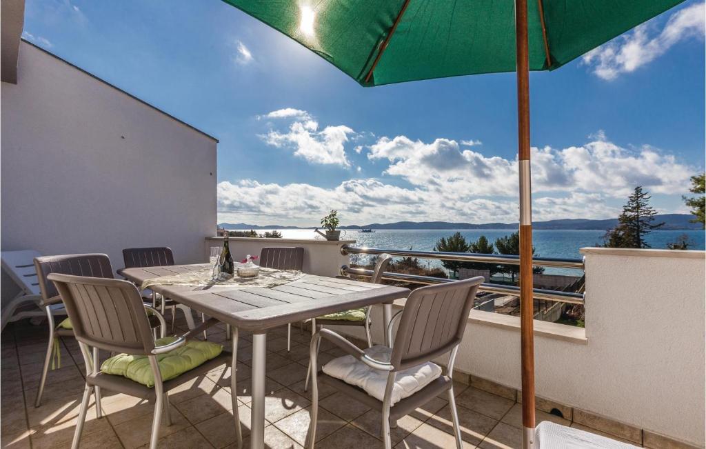 einen Tisch und Stühle auf einem Balkon mit Sonnenschirm in der Unterkunft Awesome Apartment In Zadar With Wifi in Arbanasi