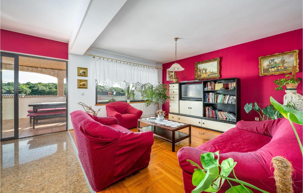 a living room with pink walls and red furniture at Cozy Apartment In Vrsar With Kitchen in Vrsar