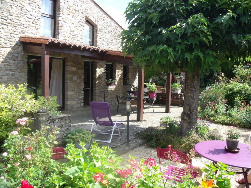 un jardín con mesas, sillas y flores en L' Esterlanges SUITE FAMILLE 2 chambres 4 personnes PROCHE PUYduFOU, en Saint-Vincent-Sterlanges