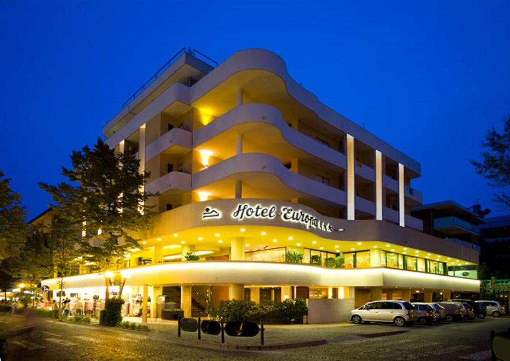 a lit up building with cars parked in front of it at Hotel Europa in Bibione