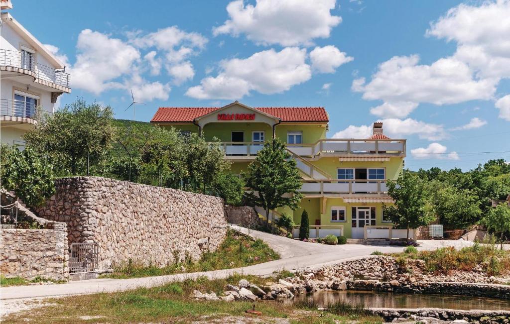una casa amarilla con una pared de piedra junto a un río en Cozy Apartment In Ribnica-krusevo With Kitchen en Anić