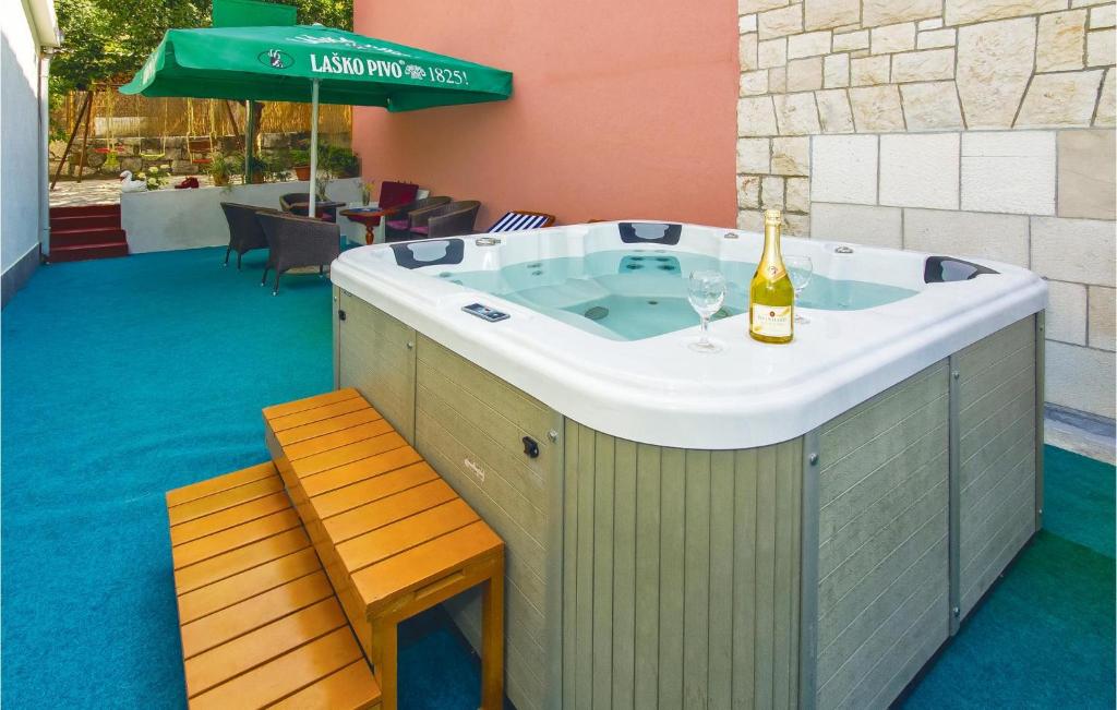 a hot tub with a bottle of champagne and a wine glass at Amazing Apartment In Ostrvica With Jacuzzi in Ostrvica