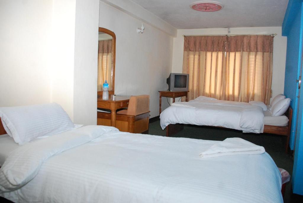 a hotel room with two beds and a television at Holyland Guest House in Kathmandu