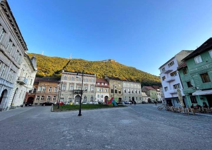 a group of buildings with a mountain in the background at Piata Sfatului Pietonal Apartment in Braşov