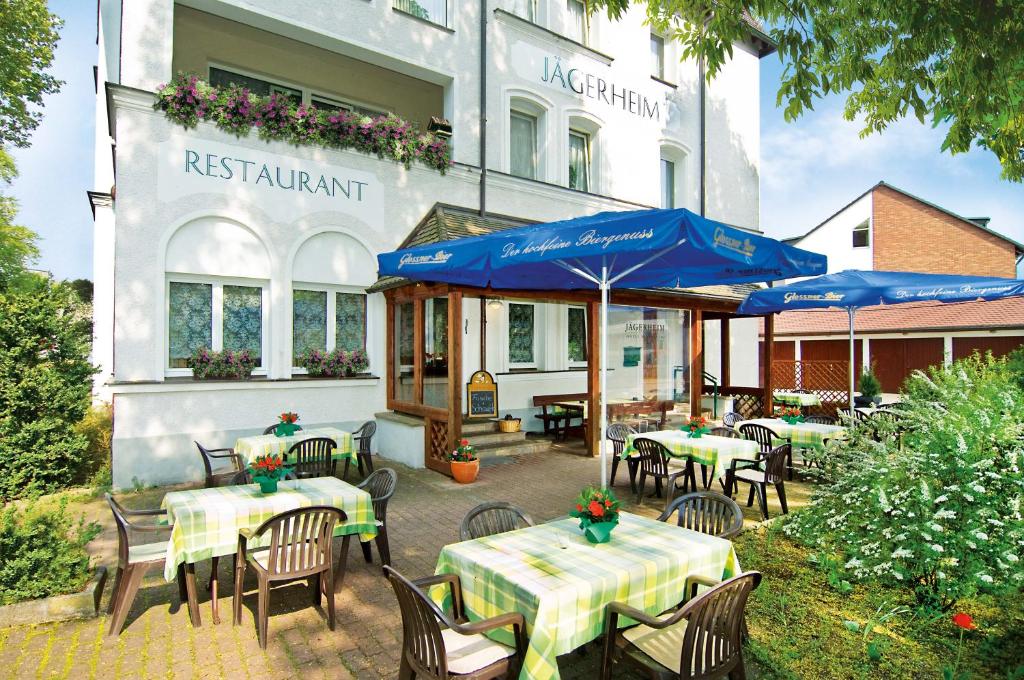 un restaurant avec des tables et des parasols en face d'un bâtiment dans l'établissement Jägerheim, à Nuremberg