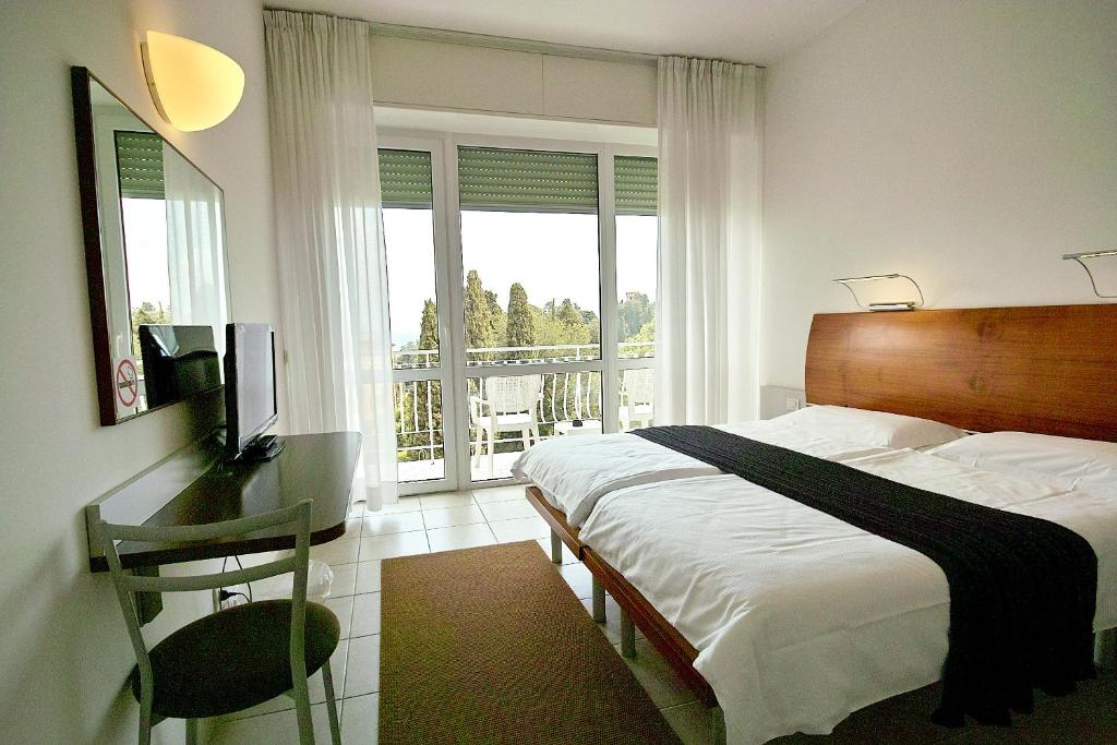a bedroom with a bed and a desk and a balcony at Hotel L'Approdo in Rapallo