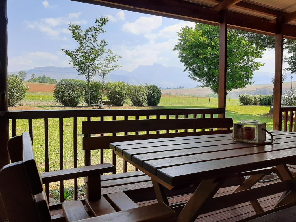a wooden table on a porch with a view of a field at Mountain Splendour Eco Resort in Winterton