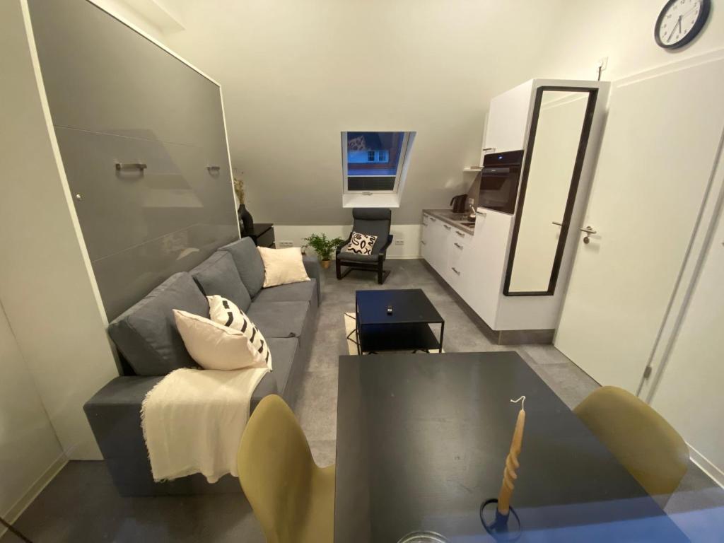 Sala de estar con sofá gris y espejo en Ferienwohnung Kirchblick, en Hungen