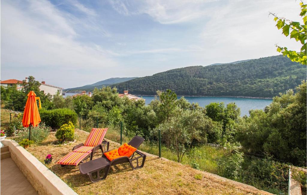 a bench and an umbrella and a view of a lake at Amazing Apartment In Labin With Kitchen in Labin