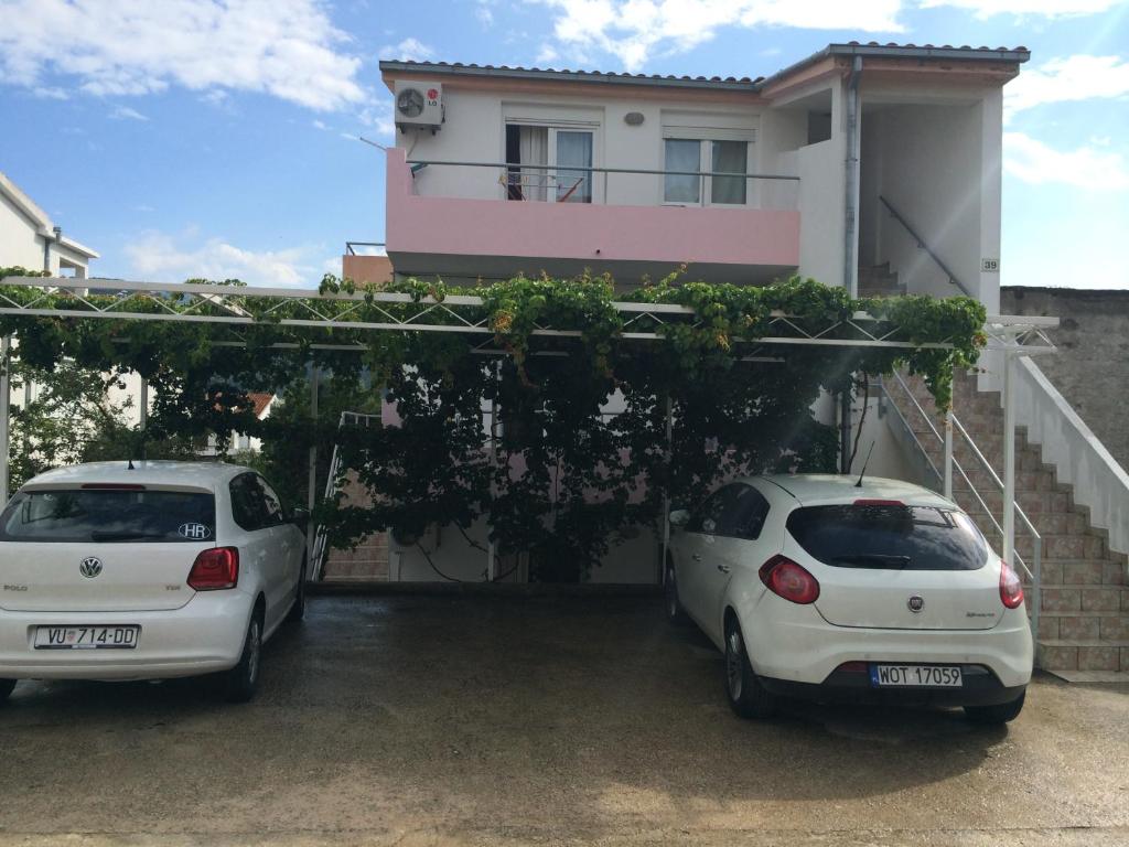 Deux voitures blanches garées devant une maison dans l'établissement Apartments Nives, à Stari Grad