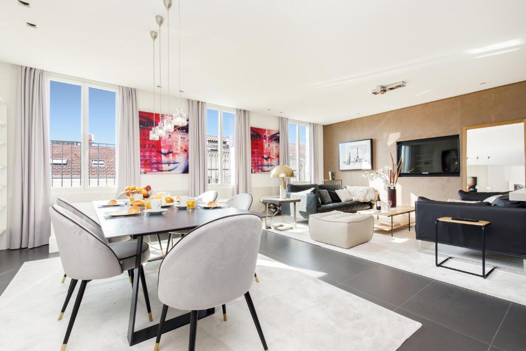 Hotel L'attique des Artistes YourHostHelper, a living room with a table and chairs and a couch at L'attique des Artistes YourHostHelper in Cannes