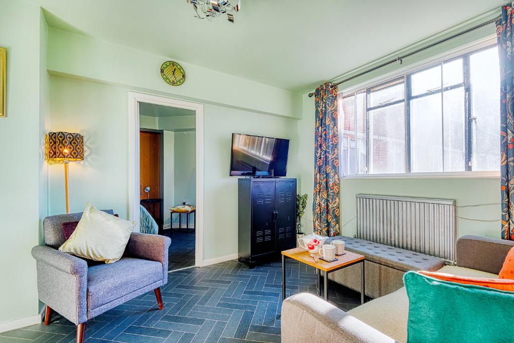uma sala de estar com um sofá e cadeiras e uma televisão em Warm and welcoming Home in Putney by UnderTheDoormat em Londres