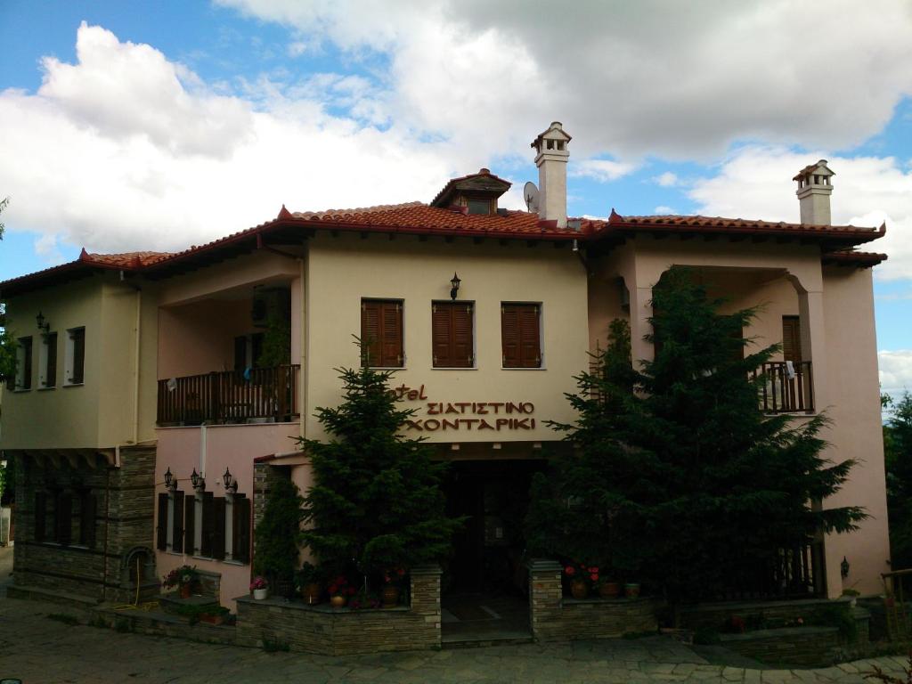 un grand bâtiment blanc avec des arbres devant lui dans l'établissement Siatistino Archontariki, à Siátista