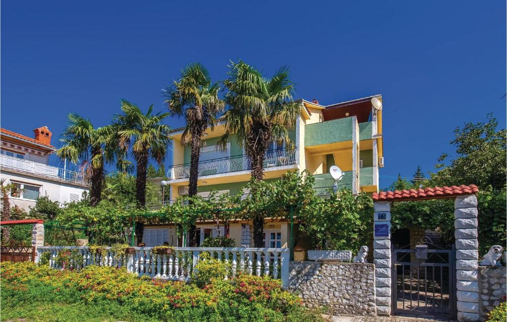 a house with palm trees and a fence at Cozy Apartment In Crikvenica With Wifi in Crikvenica